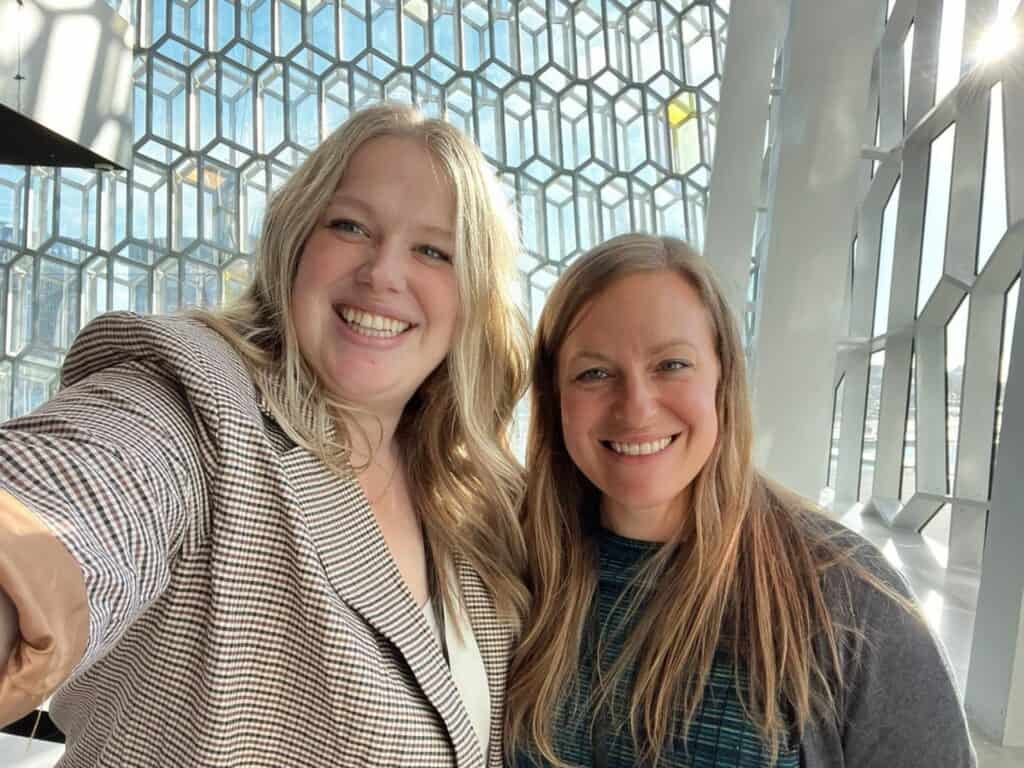 Two people smiling in front of a modern glass