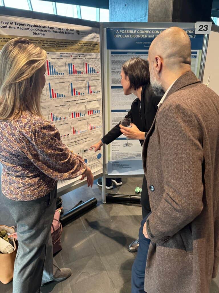 Three people engage in discussion at a research poster session