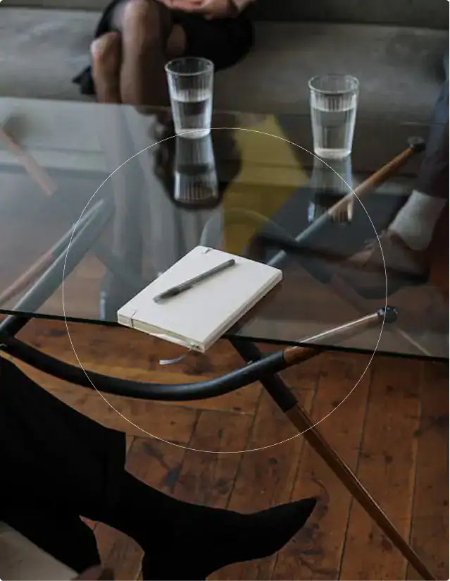 A notebook and pen on a glass table in a modern consultation room, representing patient-centered mental health care