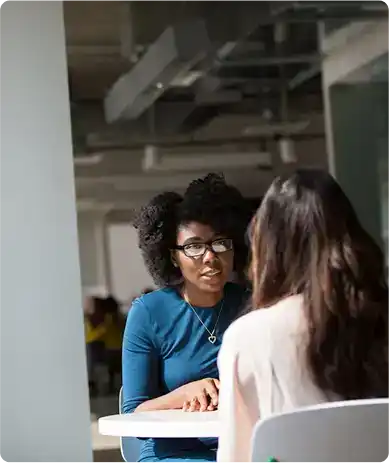 A clinical provider in a blue top consulting with a patient in a modern office for medication management