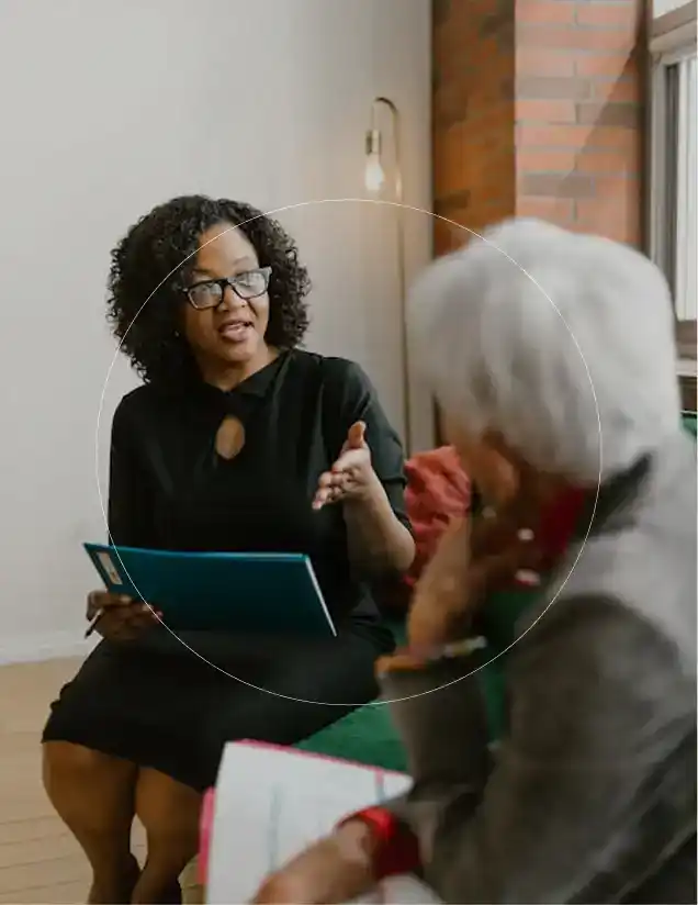 A clinical researcher with glasses and dark curly hair talking with a patient during a research study interview